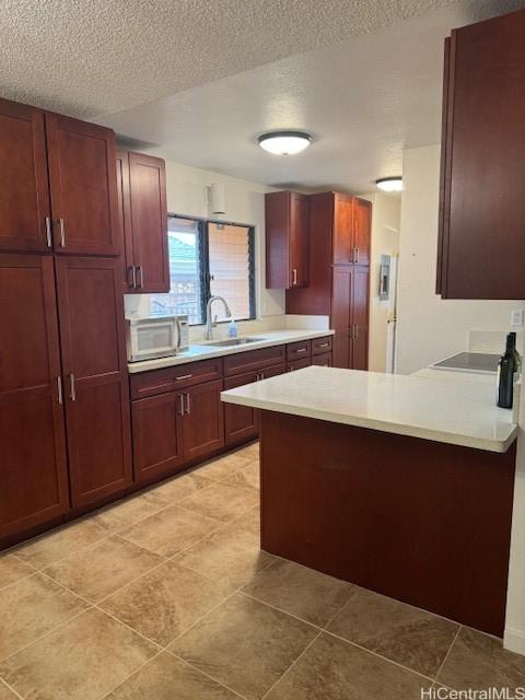 kitchen featuring kitchen peninsula, sink, black electric cooktop, and a textured ceiling