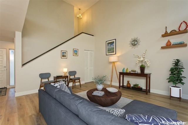 living room with a high ceiling, a notable chandelier, and light hardwood / wood-style flooring