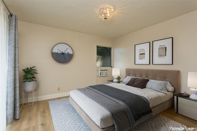 bedroom with cooling unit and light hardwood / wood-style flooring