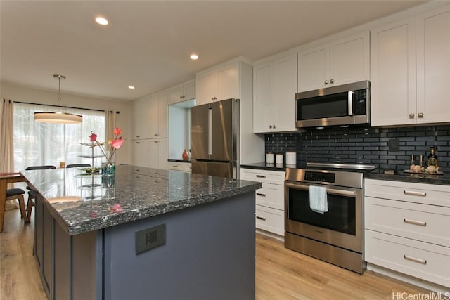 kitchen featuring dark stone countertops, appliances with stainless steel finishes, decorative backsplash, and white cabinets