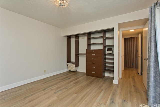 unfurnished bedroom with a textured ceiling, a closet, and light wood-type flooring