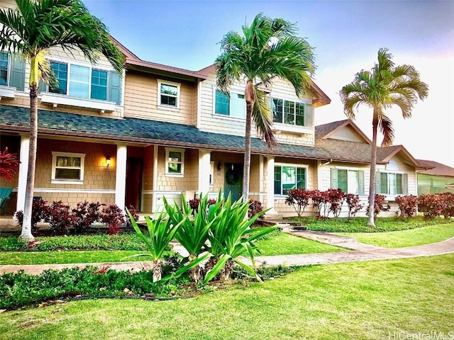 view of front of house featuring a shingled roof, a porch, and a front yard