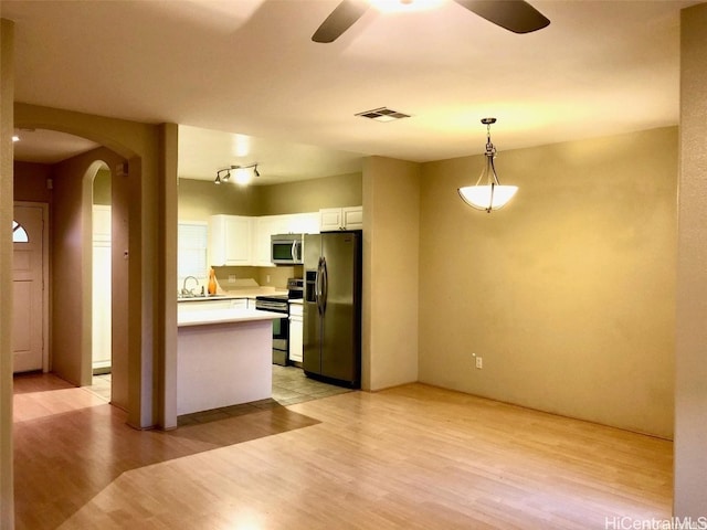 kitchen featuring ceiling fan, appliances with stainless steel finishes, decorative light fixtures, white cabinets, and sink