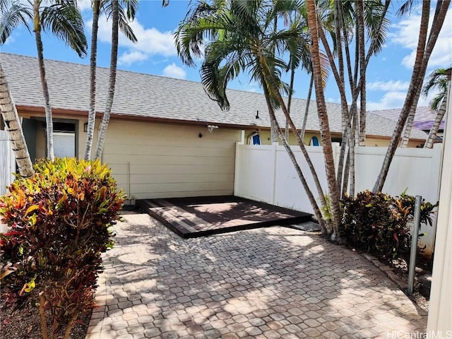 exterior space with a shingled roof and fence