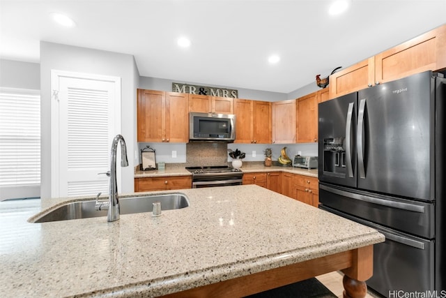 kitchen with tasteful backsplash, a breakfast bar, sink, light stone countertops, and stainless steel appliances