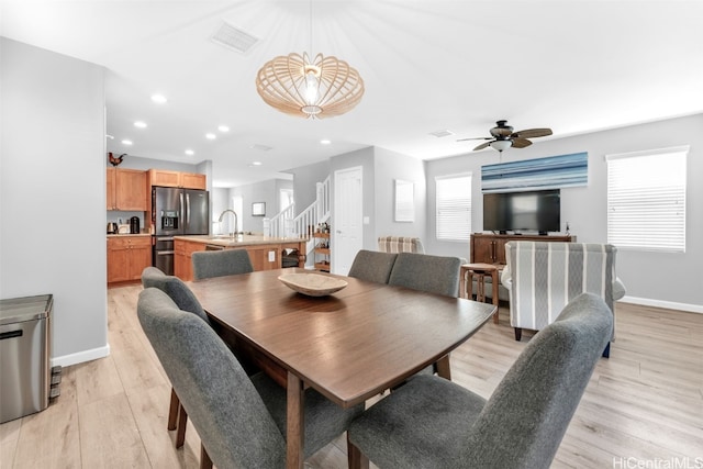 dining area with ceiling fan, light hardwood / wood-style flooring, and sink