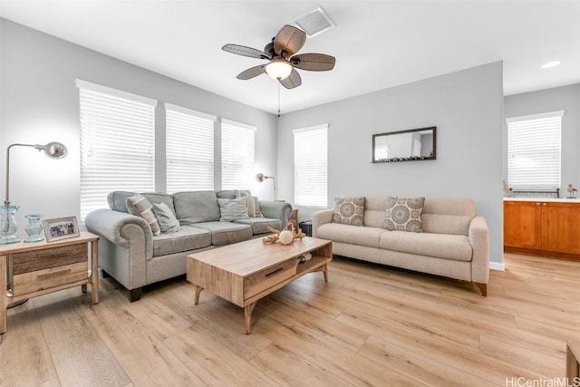 living room with light hardwood / wood-style floors, ceiling fan, and a healthy amount of sunlight