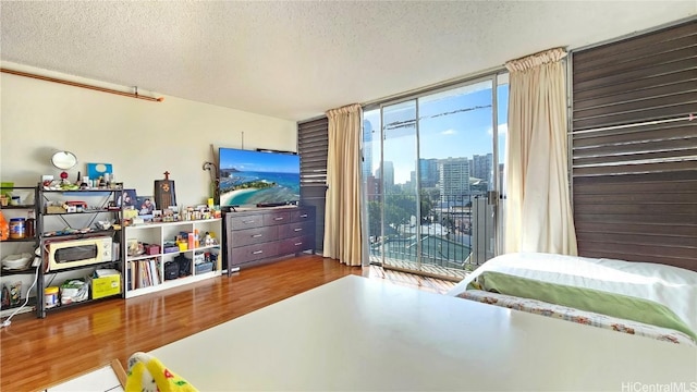 bedroom with hardwood / wood-style floors, multiple windows, a textured ceiling, and access to outside