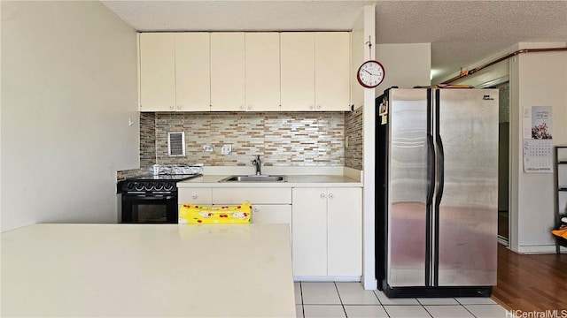 kitchen featuring decorative backsplash, black range with electric cooktop, white cabinets, sink, and stainless steel fridge