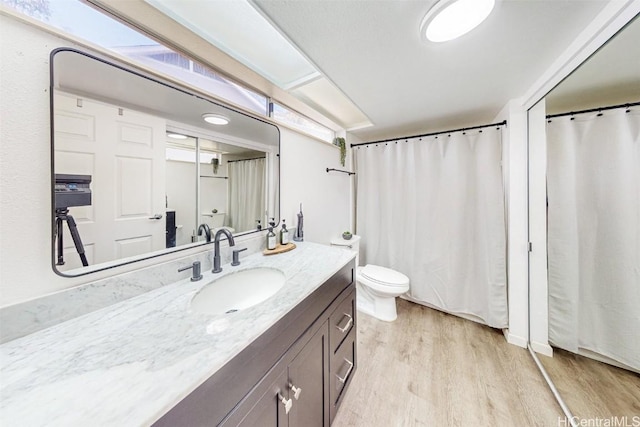 full bathroom with a shower with shower curtain, wood finished floors, toilet, and vanity