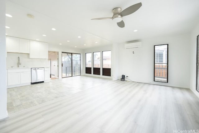 unfurnished living room featuring sink, light hardwood / wood-style flooring, an AC wall unit, and ceiling fan