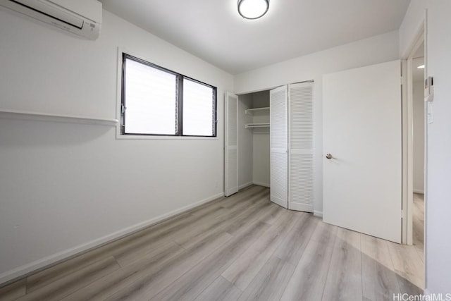 unfurnished bedroom featuring light hardwood / wood-style flooring, a wall mounted air conditioner, and a closet