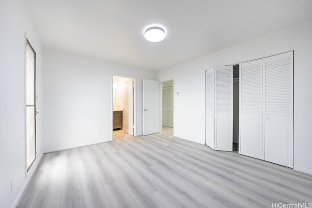 unfurnished bedroom featuring ensuite bathroom, light hardwood / wood-style floors, and a closet