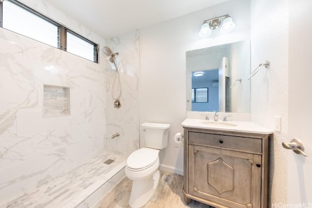 bathroom with vanity, toilet, and a tile shower