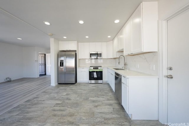 kitchen featuring sink, white cabinetry, appliances with stainless steel finishes, light hardwood / wood-style floors, and backsplash