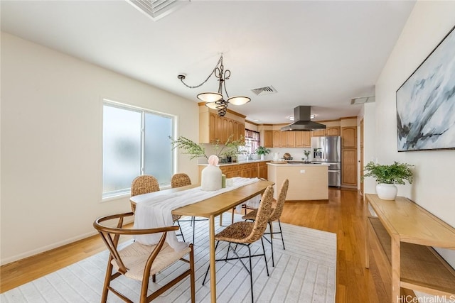 dining area with visible vents, light wood-style flooring, and baseboards