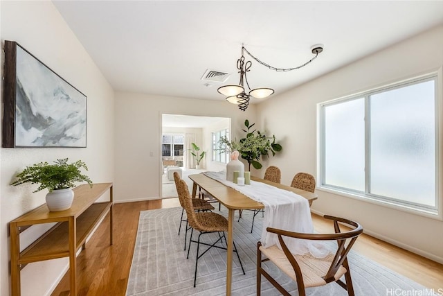 dining room featuring baseboards, visible vents, and light wood-style floors