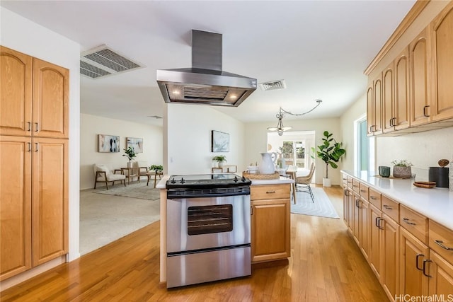 kitchen with light wood-style flooring, visible vents, stainless steel range with electric cooktop, light countertops, and island exhaust hood