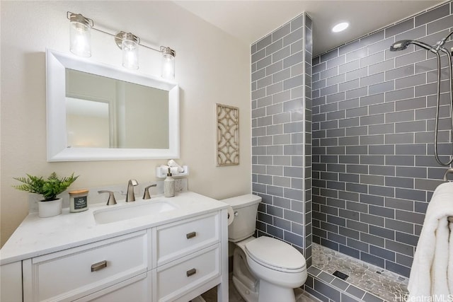 full bath with a tile shower, vanity, and toilet