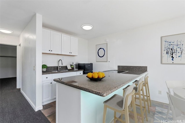 kitchen featuring dark hardwood / wood-style flooring, a breakfast bar, sink, and white cabinets