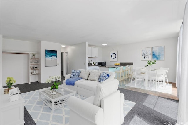 living room featuring dark colored carpet and sink