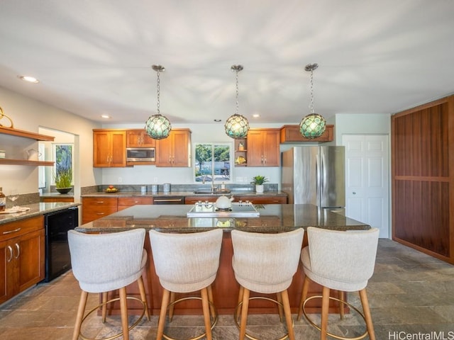 kitchen featuring appliances with stainless steel finishes, a center island, sink, and hanging light fixtures