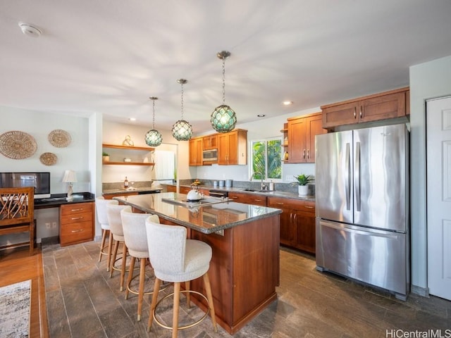 kitchen featuring appliances with stainless steel finishes, sink, hanging light fixtures, a center island, and dark wood-type flooring