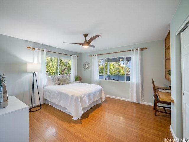 bedroom featuring multiple windows, hardwood / wood-style floors, and ceiling fan