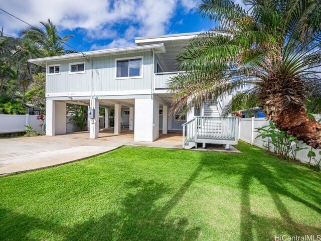 rear view of property featuring a lawn and a carport