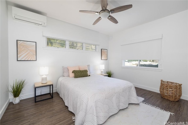 bedroom with multiple windows, dark wood-type flooring, a wall mounted AC, and ceiling fan