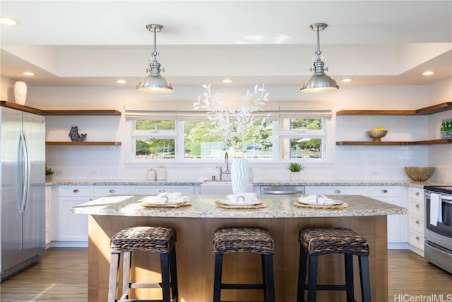 kitchen with a kitchen bar, a center island, white cabinets, and appliances with stainless steel finishes