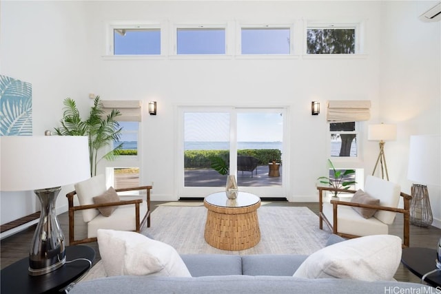 living room featuring wood-type flooring, a towering ceiling, and a wall mounted AC