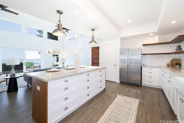 kitchen with a kitchen island, dark hardwood / wood-style floors, pendant lighting, white cabinets, and stainless steel fridge