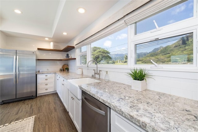 kitchen with sink, stainless steel appliances, dark hardwood / wood-style floors, light stone countertops, and white cabinets