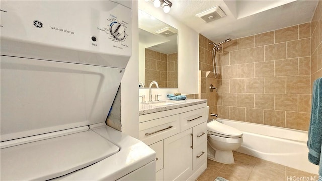 full bathroom with toilet, washer / dryer, tiled shower / bath combo, tile patterned flooring, and vanity