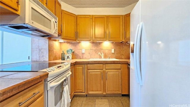 kitchen with white appliances, tasteful backsplash, sink, tile countertops, and light tile patterned flooring