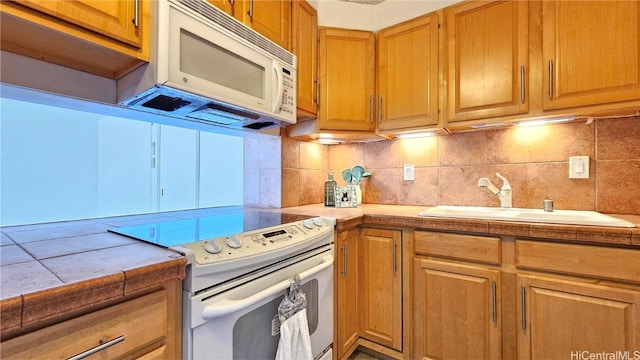 kitchen with sink, white appliances, tile countertops, and tasteful backsplash