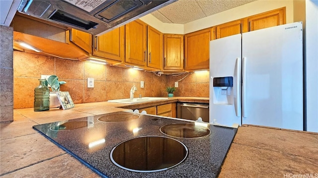 kitchen featuring dishwasher, white refrigerator with ice dispenser, sink, backsplash, and tile counters