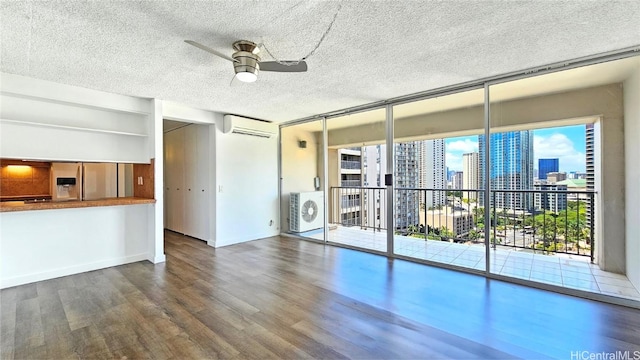 interior space featuring washer / dryer, hardwood / wood-style floors, a wall mounted air conditioner, floor to ceiling windows, and ceiling fan