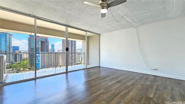 empty room with hardwood / wood-style flooring, expansive windows, and ceiling fan