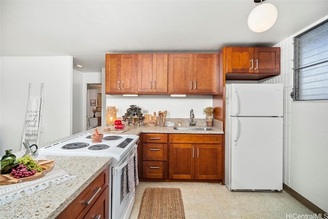 kitchen featuring sink, white appliances, and light stone counters