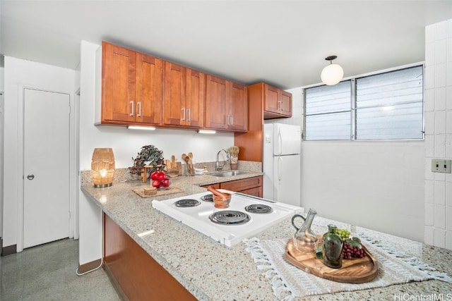 kitchen with light stone countertops, sink, range, and white refrigerator