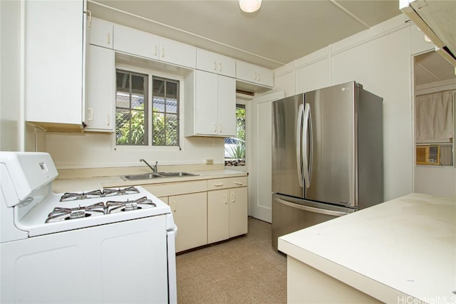 kitchen featuring sink, white range with gas cooktop, white cabinetry, and stainless steel fridge