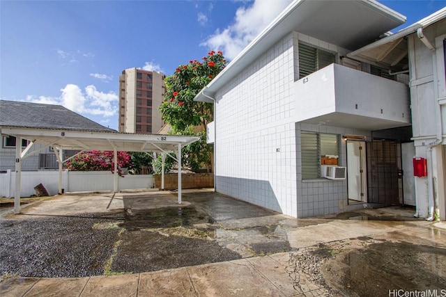 view of property exterior with a balcony, cooling unit, and a carport