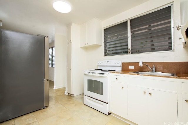 kitchen featuring stainless steel fridge, sink, white electric range oven, white cabinetry, and decorative backsplash