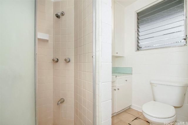 bathroom with a tile shower, toilet, and tile patterned floors