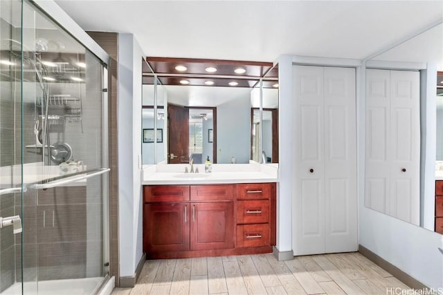 bathroom with a shower with shower door, vanity, and wood-type flooring