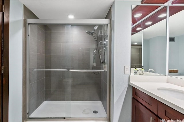 bathroom featuring a shower with shower door and vanity