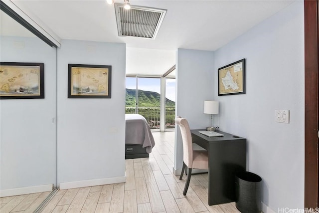 office space featuring expansive windows, a mountain view, and light hardwood / wood-style floors