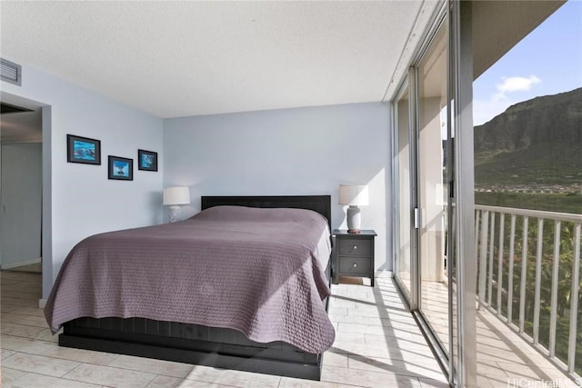 bedroom featuring a textured ceiling, floor to ceiling windows, and a mountain view